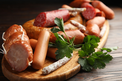 Different tasty sausages on wooden table, closeup