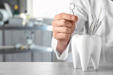 Photo of Dentist with professional tools at table in clinic, closeup. Space for text