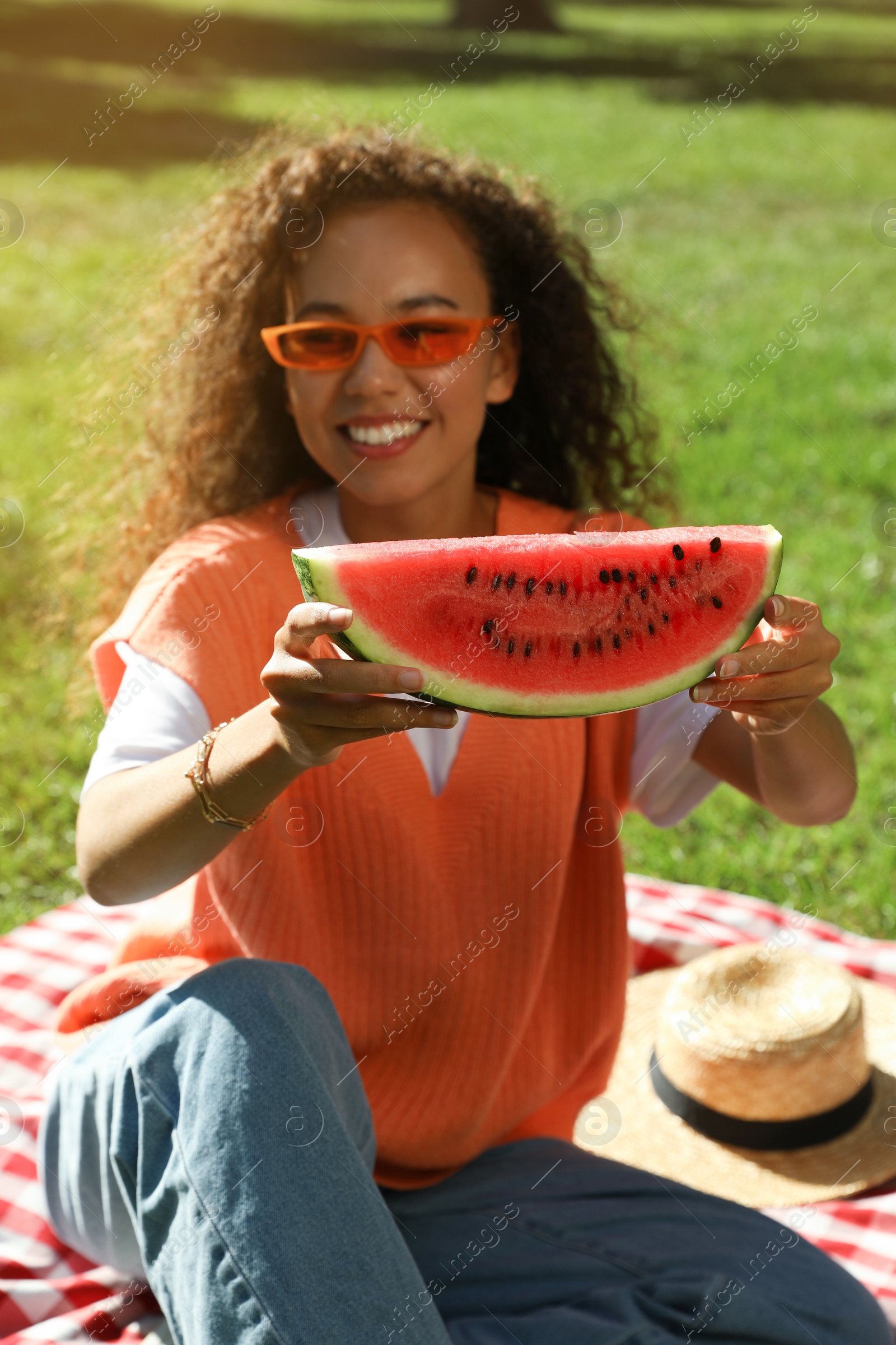 Photo of Beautiful young African American woman with slice of watermelon in park