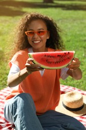 Photo of Beautiful young African American woman with slice of watermelon in park