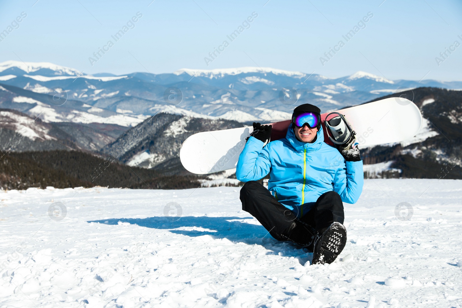 Photo of Happy man with snowboard in mountains. Winter vacation