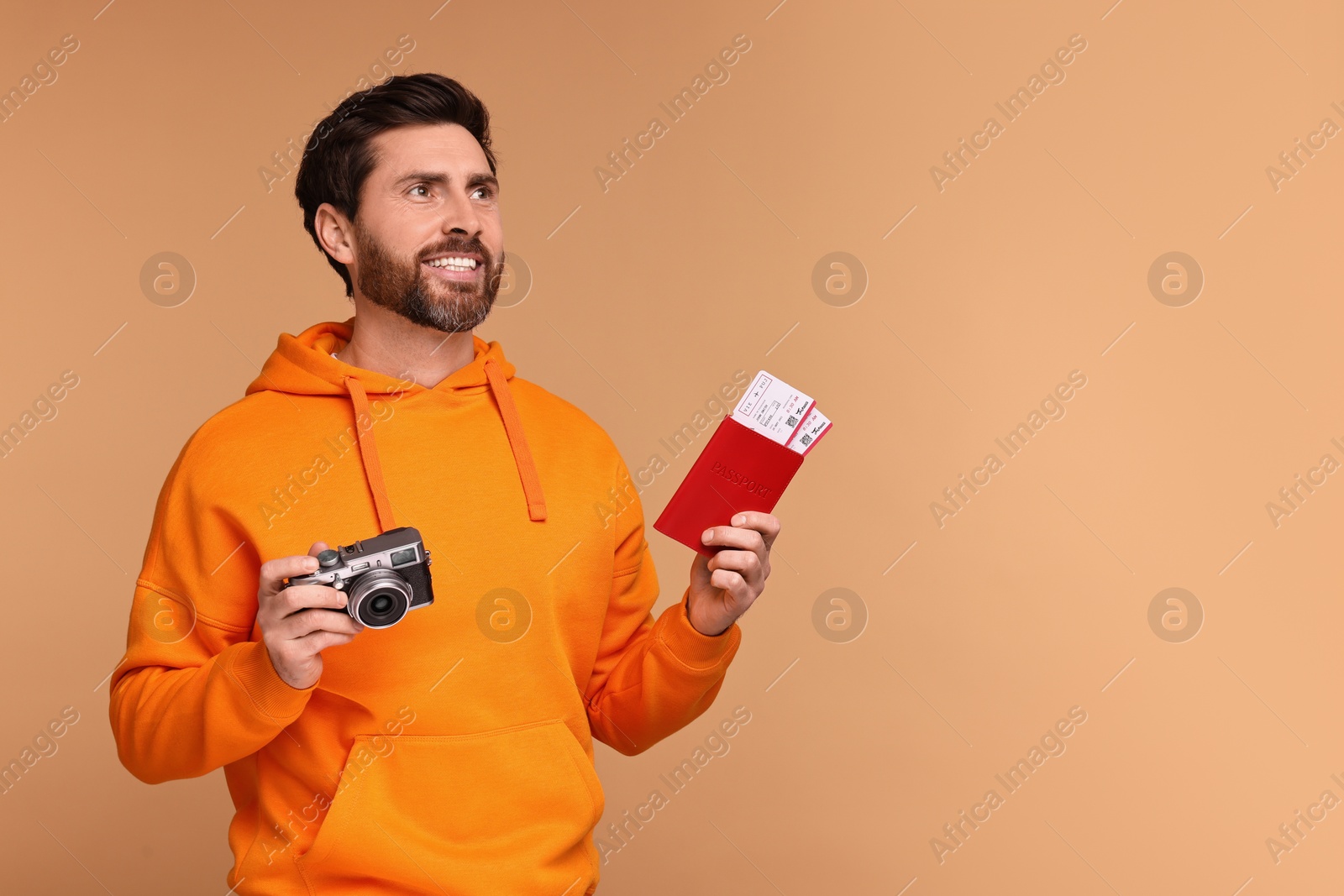 Photo of Smiling man with passport, camera and tickets on beige background. Space for text