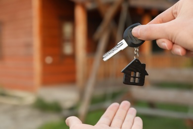 Photo of Real estate agent giving key to buyer on blurred background, focus on hands