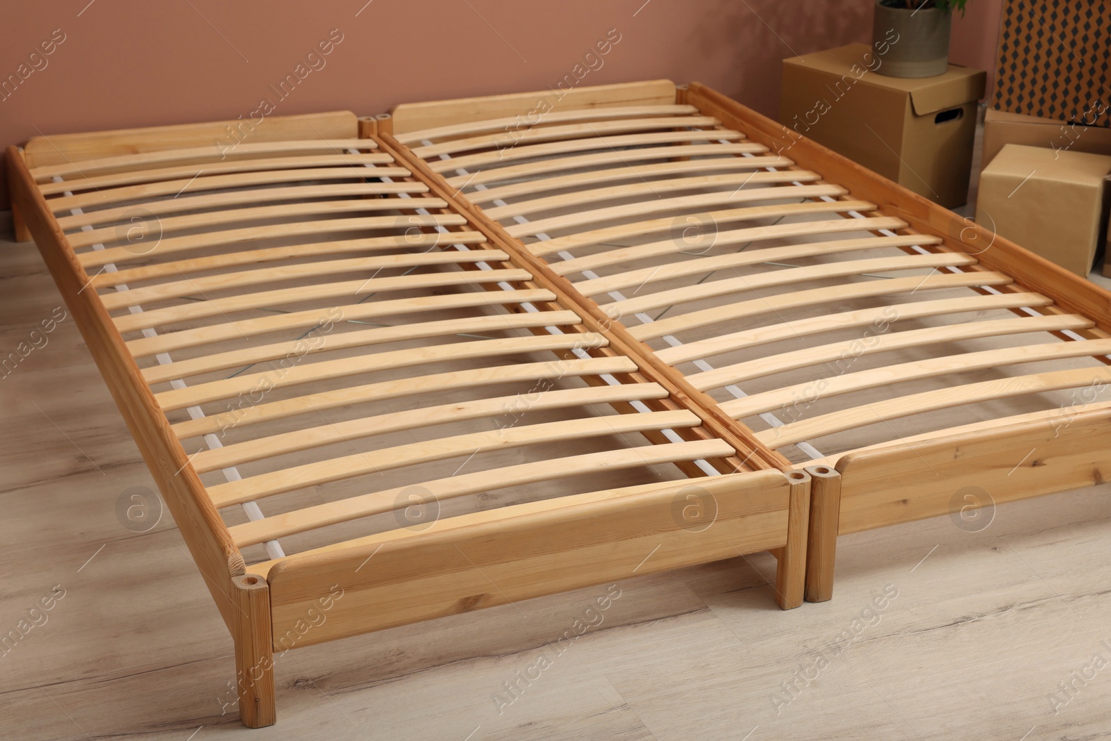 Photo of Wooden bed frame and cardboard boxes on floor in room