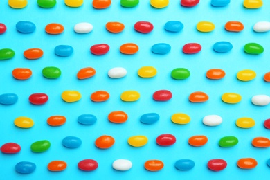 Photo of Tasty colorful jelly beans on blue background, flat lay