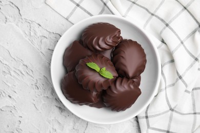 Photo of Delicious chocolate covered zephyrs with mint in bowl on light grey background, top view