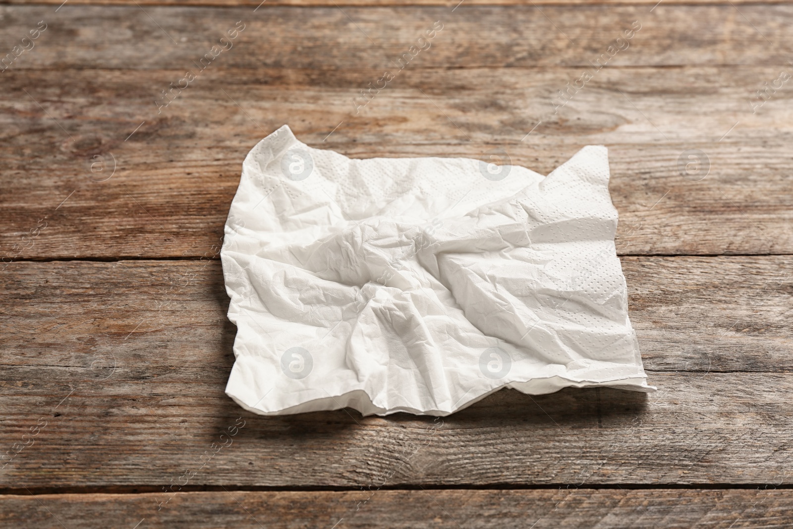 Photo of Crumpled napkin on wooden background. Personal hygiene