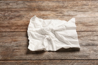 Photo of Crumpled napkin on wooden background. Personal hygiene