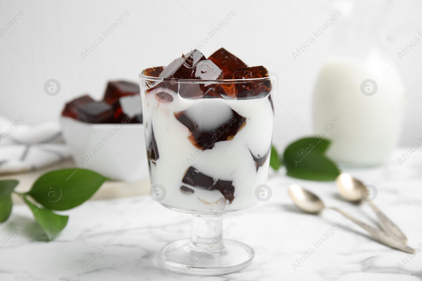 Photo of Glass of milk with delicious grass jelly on white marble table