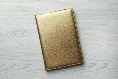 Photo of Golden planner on white wooden table, top view
