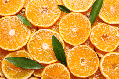 Photo of Slices of fresh ripe tangerines and leaves as background, top view. Citrus fruit