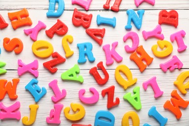 Photo of Colorful magnetic letters on white wooden table, flat lay