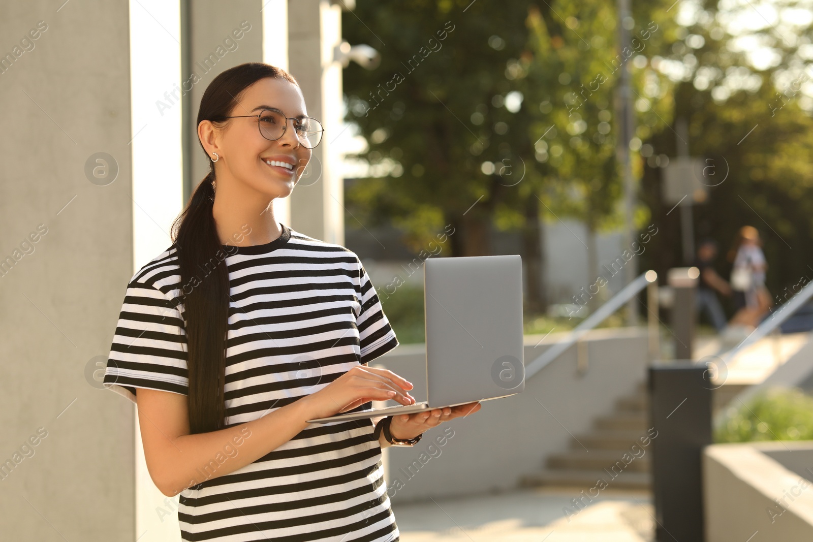 Photo of Happy young woman using modern laptop outdoors. Space for text