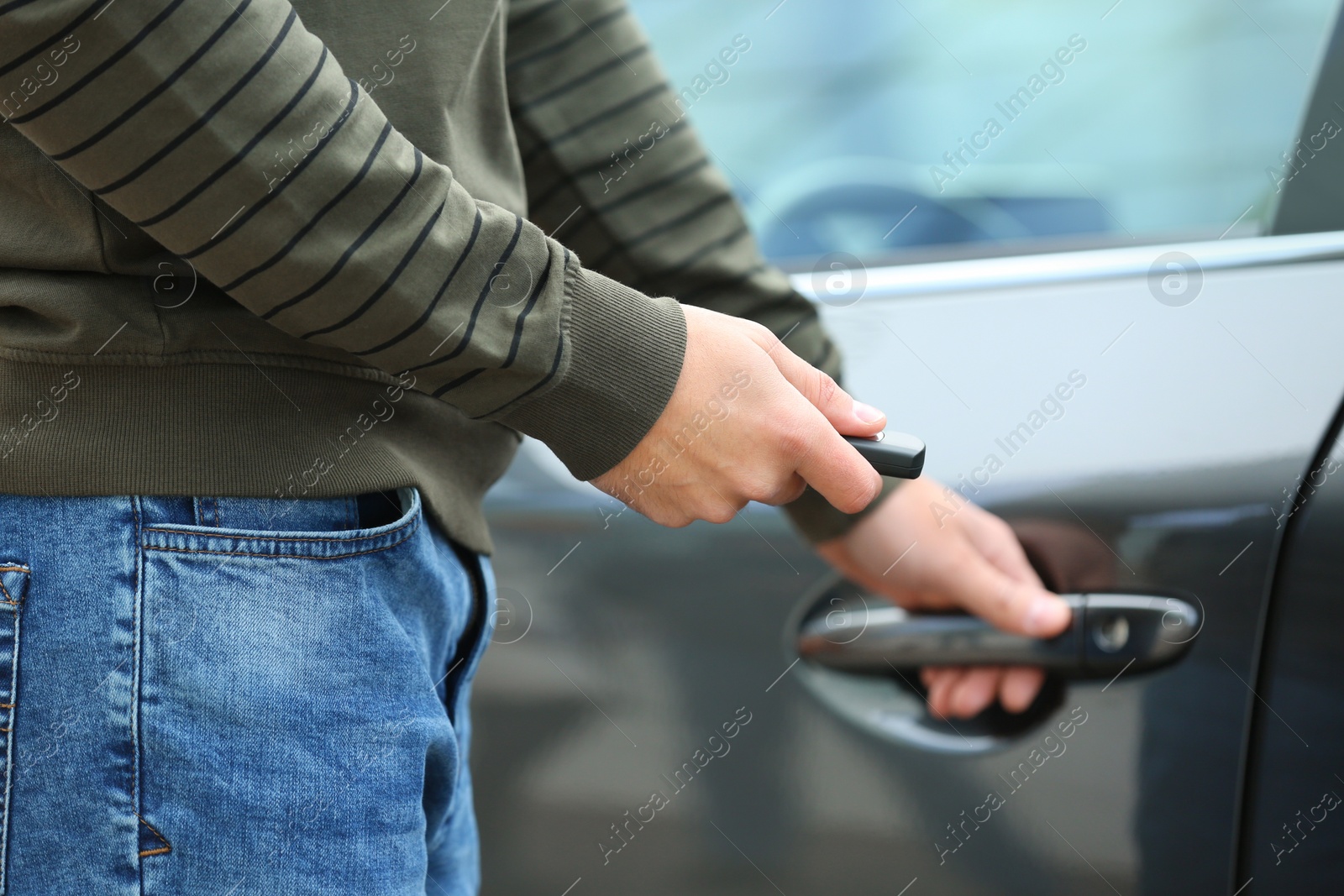 Photo of Closeup view of man opening car door with remote key