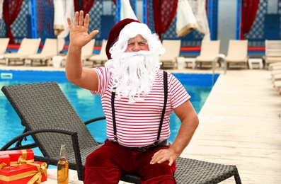 Photo of Authentic Santa Claus on lounge chair near pool at resort