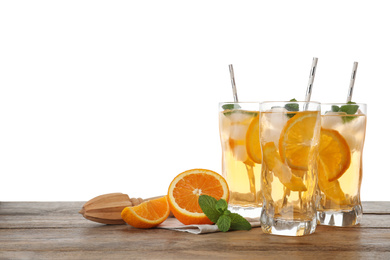 Photo of Delicious refreshing drink with orange slices, mint and squeezer on wooden table against white background. Space for text