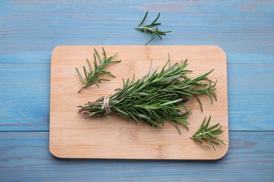 Photo of Bunch of fresh rosemary on light blue wooden table, top view