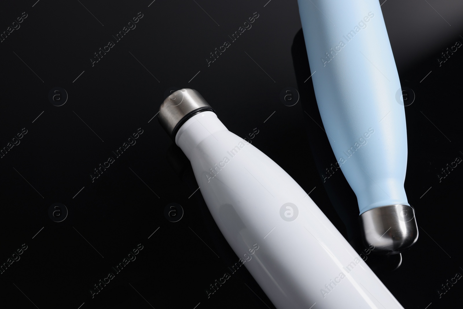 Photo of Stylish thermo bottles on black background, flat lay. Space for text