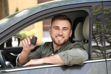 Happy man with car key in his new auto 