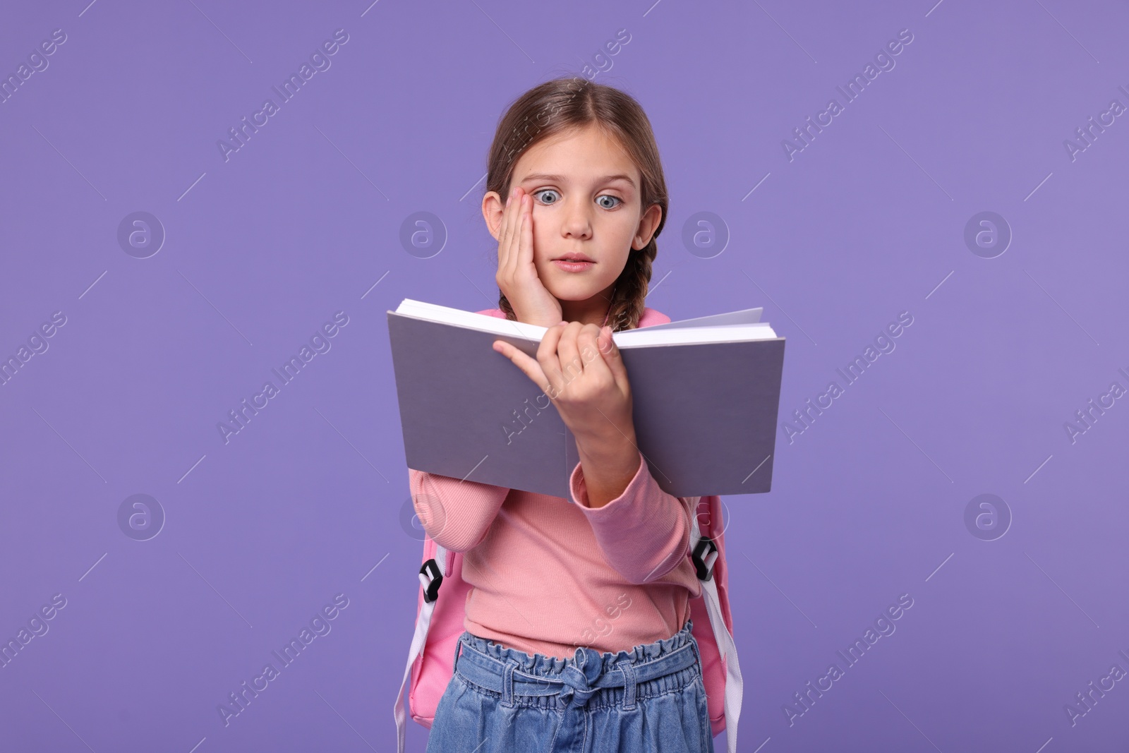 Photo of Schoolgirl with open book on violet background