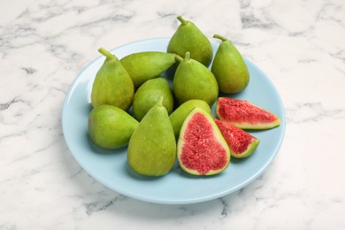 Photo of Cut and whole green figs on white marble table