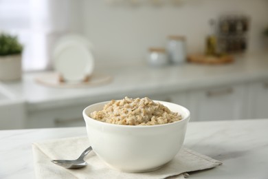 Photo of Breakfast time. Tasty oatmeal in bowl on white marble table