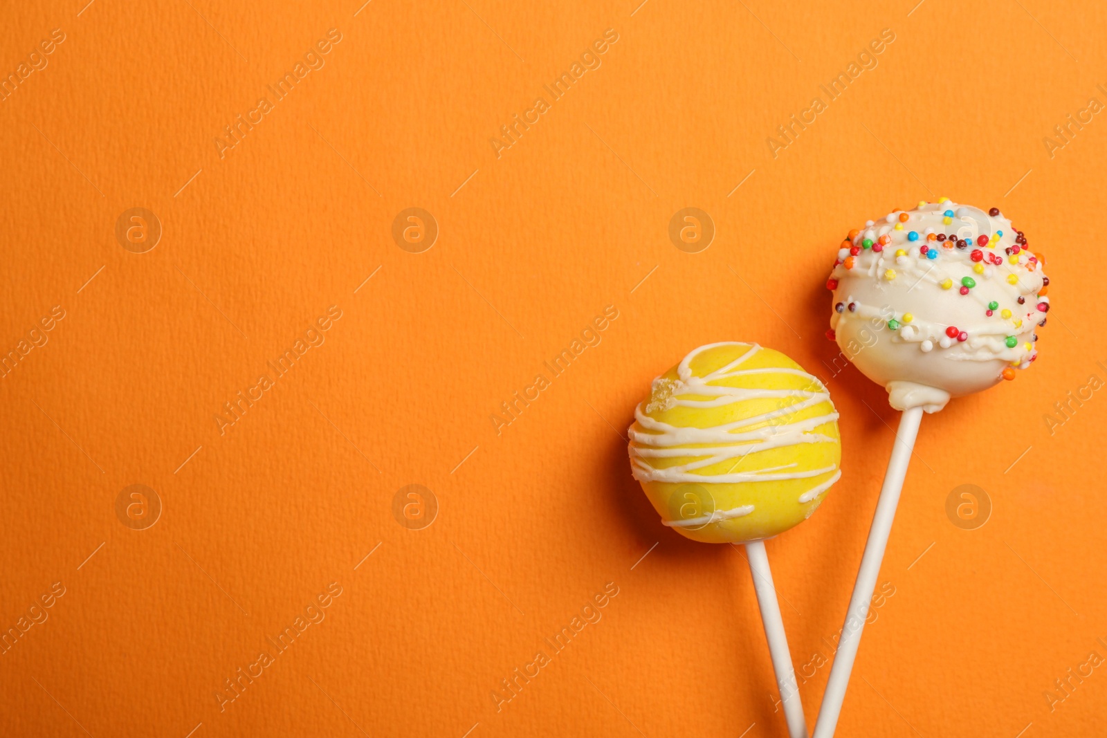 Photo of Bright delicious cake pops on color background, flat lay. Space for text