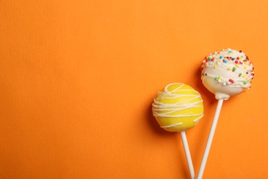 Photo of Bright delicious cake pops on color background, flat lay. Space for text