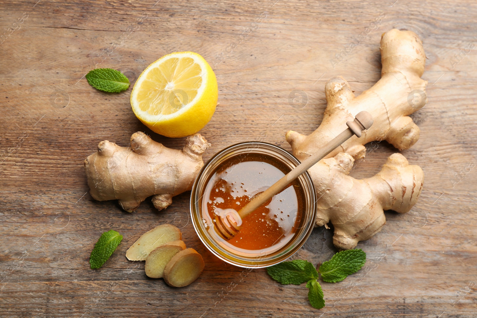 Photo of Ginger, honey, mint and lemon on wooden table, flat lay. Natural cold remedies