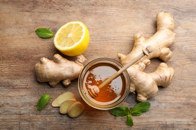 Photo of Ginger, honey, mint and lemon on wooden table, flat lay. Natural cold remedies