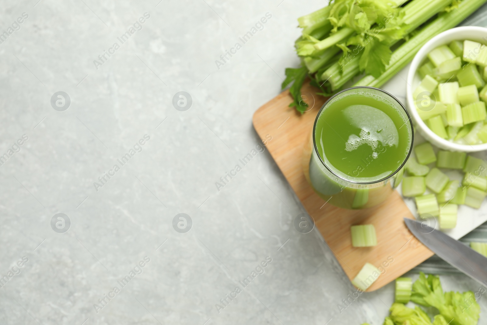 Photo of Glass of delicious celery juice and vegetables on grey table, flat lay. Space for text