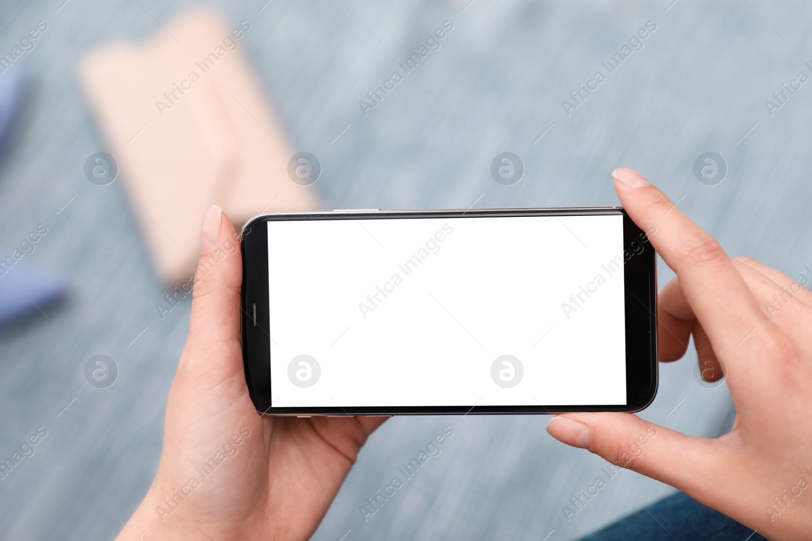 Photo of Woman holding smartphone with blank screen indoors, closeup of hands. Space for text