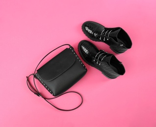 Photo of Pair of stylish ankle boots and bag on pink background, flat lay