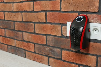 Photo of Compact electric heater charging from socket indoors, closeup. Space for text