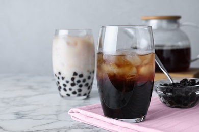 Refreshing iced tea and bowl with tapioca balls on white marble table. Space for text