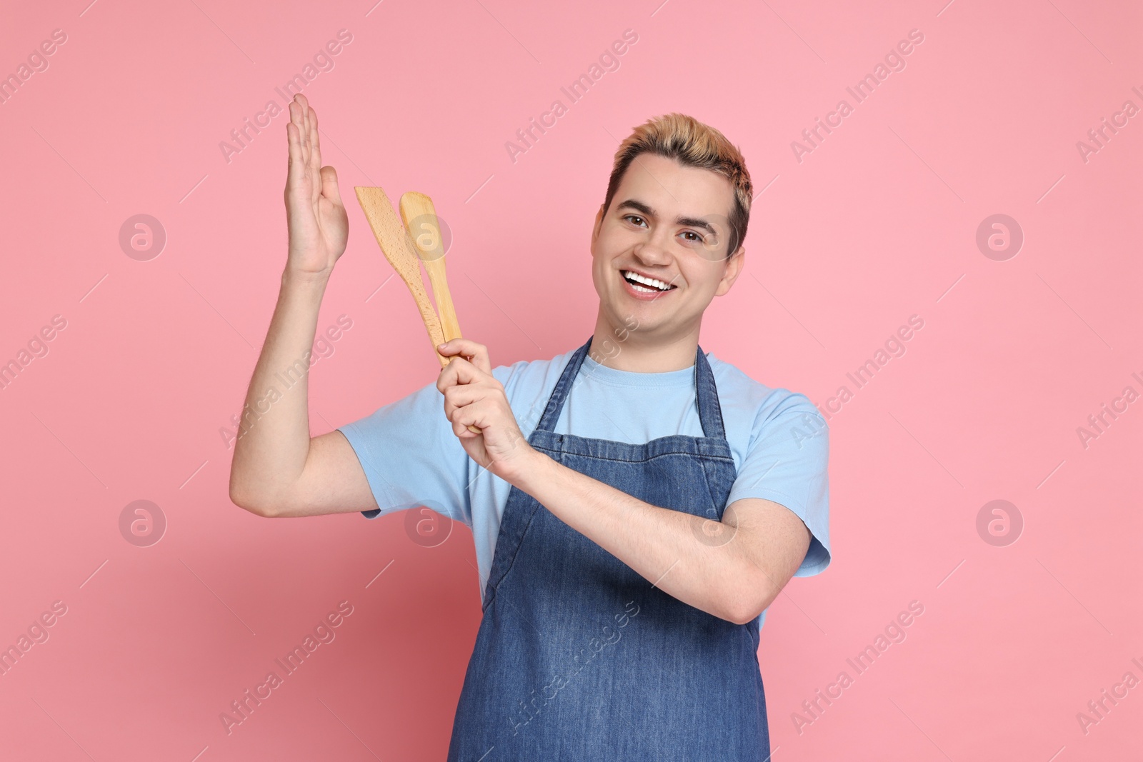 Photo of Portrait of happy confectioner holding spatulas on pink background