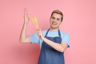 Portrait of happy confectioner holding spatulas on pink background