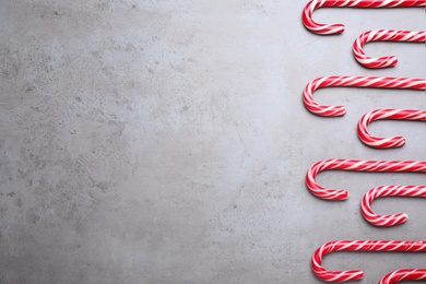 Sweet Christmas candy canes on grey background, flat lay. Space for text