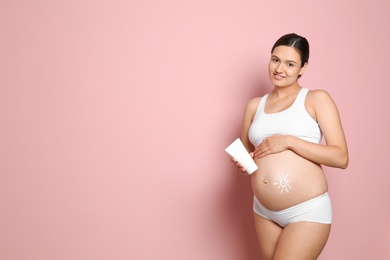 Photo of Sun painted with body cream on pregnant woman's belly against color background. Space for text