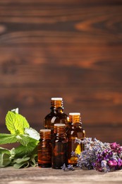 Photo of Bottles with essential oils, herbs and flowers on wooden table. Space for text