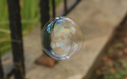 Photo of One beautiful clear soap bubble floating outdoors