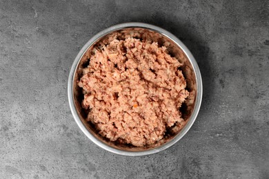 Photo of Wet pet food in feeding bowl on grey stone background, top view
