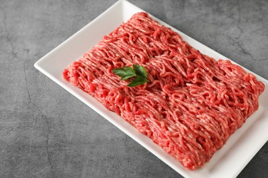 Photo of Raw ground meat and parsley on grey table