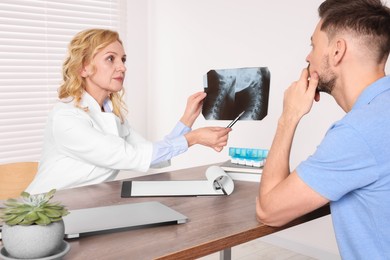 Photo of Doctor with X-ray image consulting patient in clinic