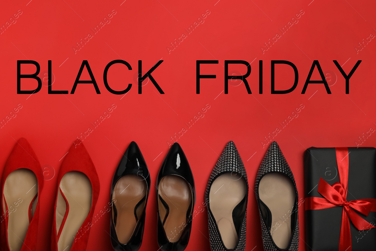 Photo of Stylish women's shoes, gift box and phrase Black Friday on red background, flat lay