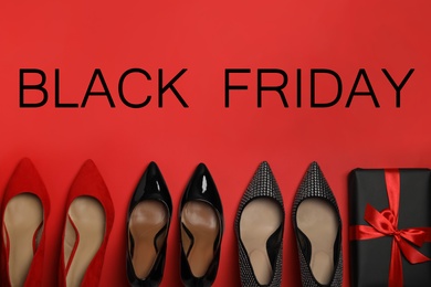 Photo of Stylish women's shoes, gift box and phrase Black Friday on red background, flat lay