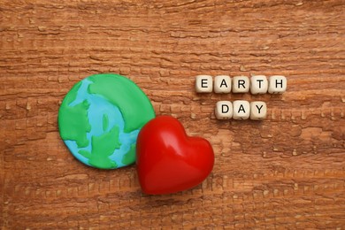 Photo of Cubes with words Earth Day, plasticine planet and decorative heart on wooden table, flat lay