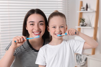 Mother and her daughter brushing teeth together in bathroom