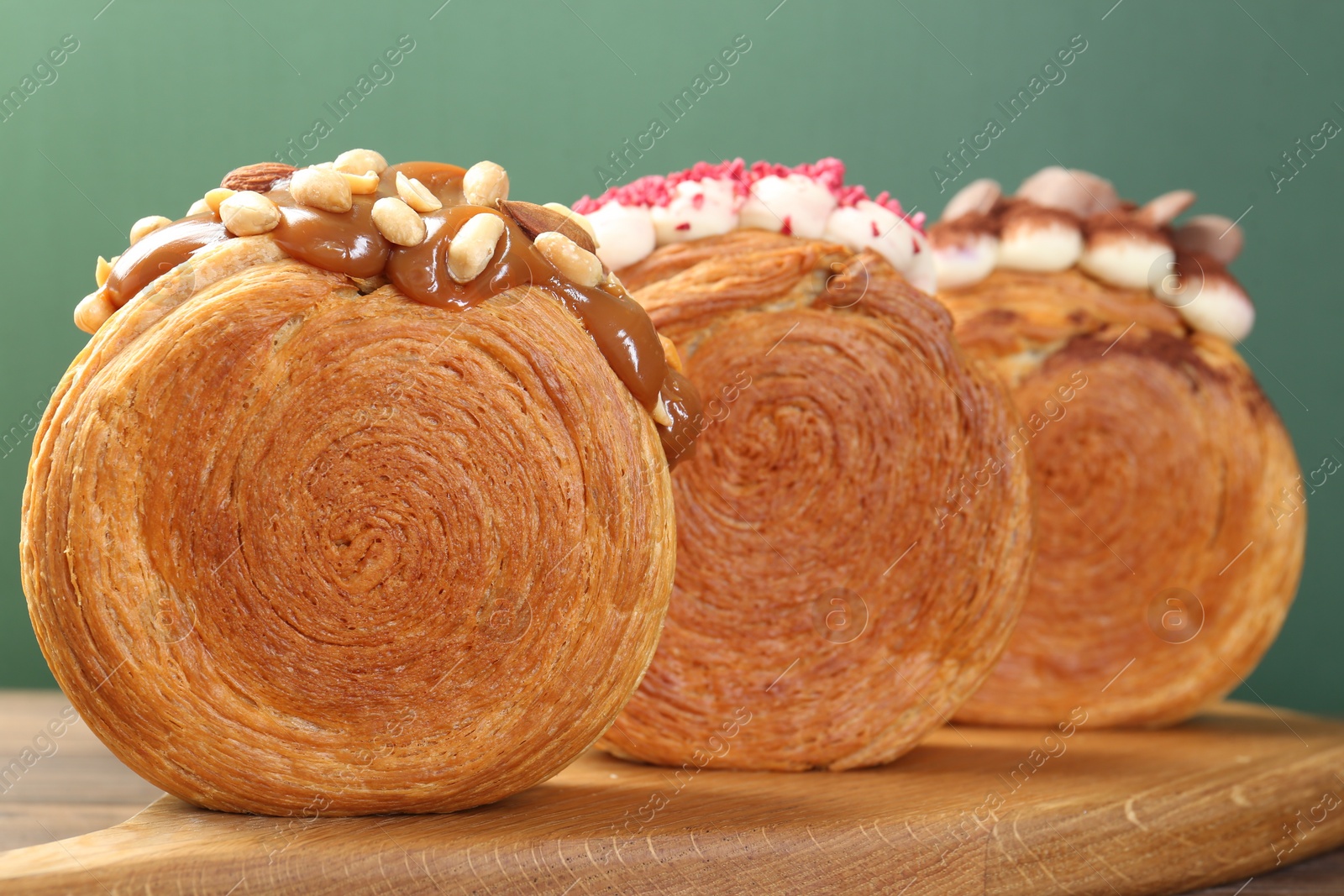 Photo of Crunchy round croissants on wooden board, closeup. Tasty puff pastry