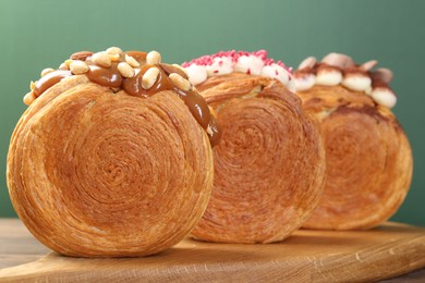Photo of Crunchy round croissants on wooden board, closeup. Tasty puff pastry